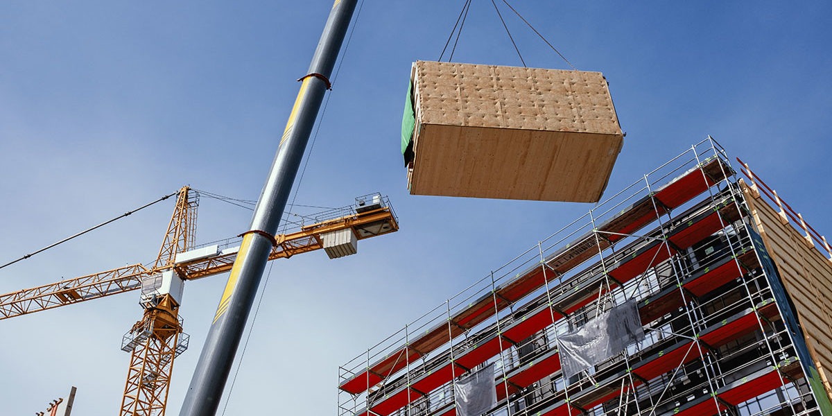 Crane lifting a prefabricated building module to its position in the structure
