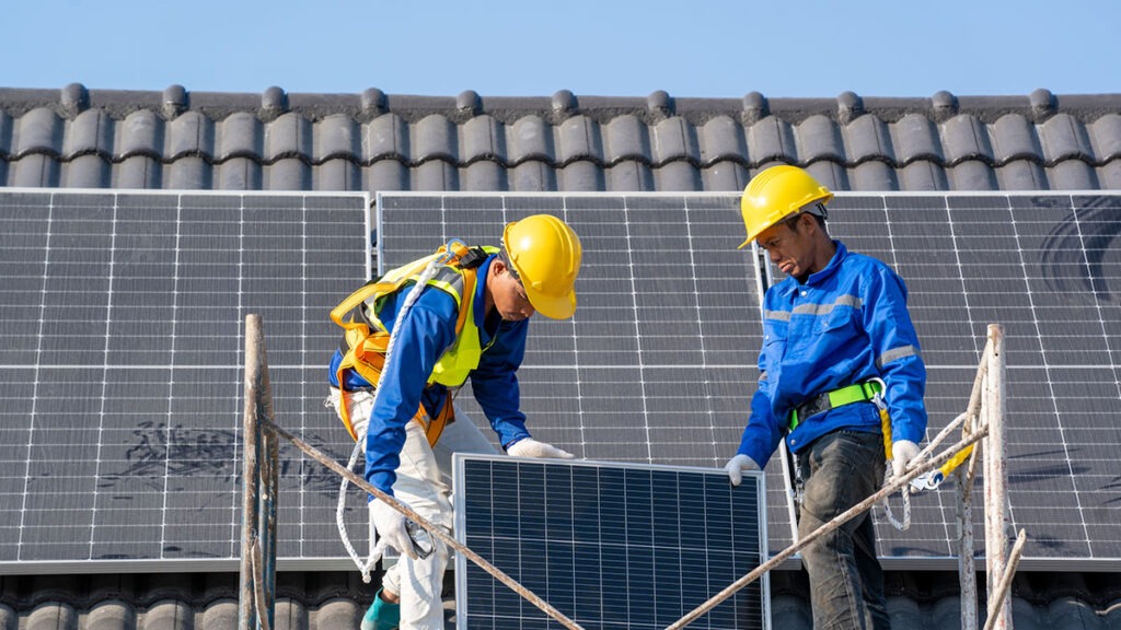 Professional worker installs solar panels on the roof of a energy efficient green home.
