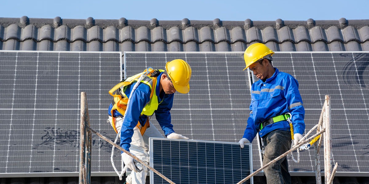 Professional worker installs solar panels on the roof of a energy efficient green home.