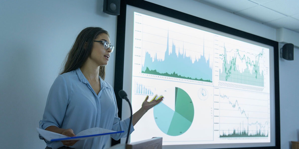 Businesswoman making presentation using screen of charts and graphs in business meeting