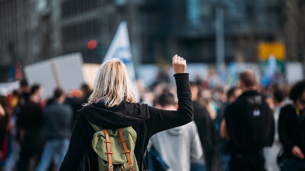 Rear view of a female protester raising her fist up