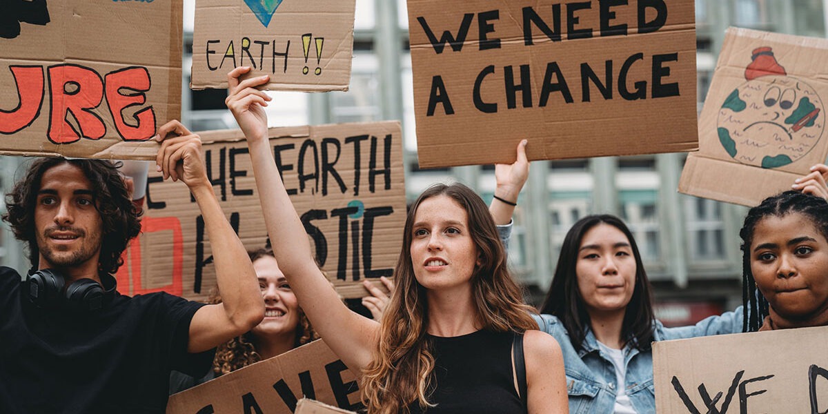 A group of young adult people are marching together on strike against climate change