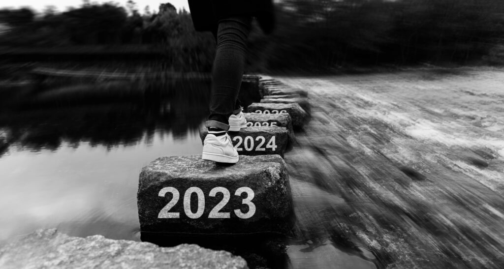 Woman crossing stepping stones with new year number 2023, 2024 and 2025